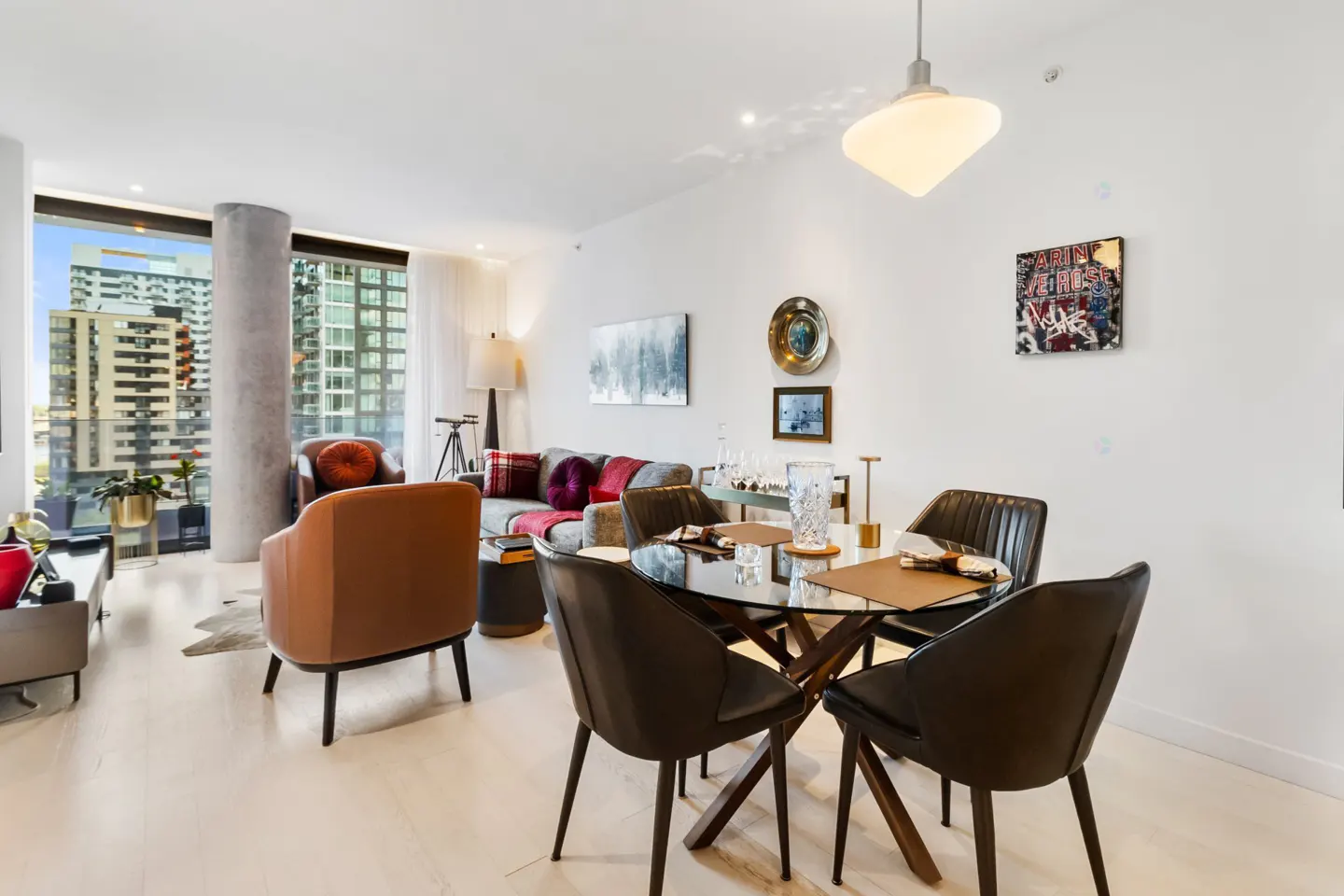 Bright, modern condo interior with a glass dining table, leather chairs, and city views.