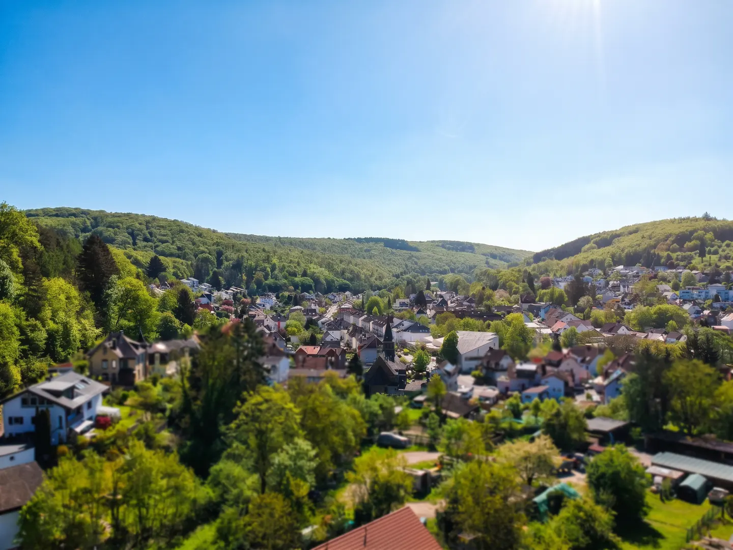 Aerial view of a village nestled in a green valley under a clear blue sky.