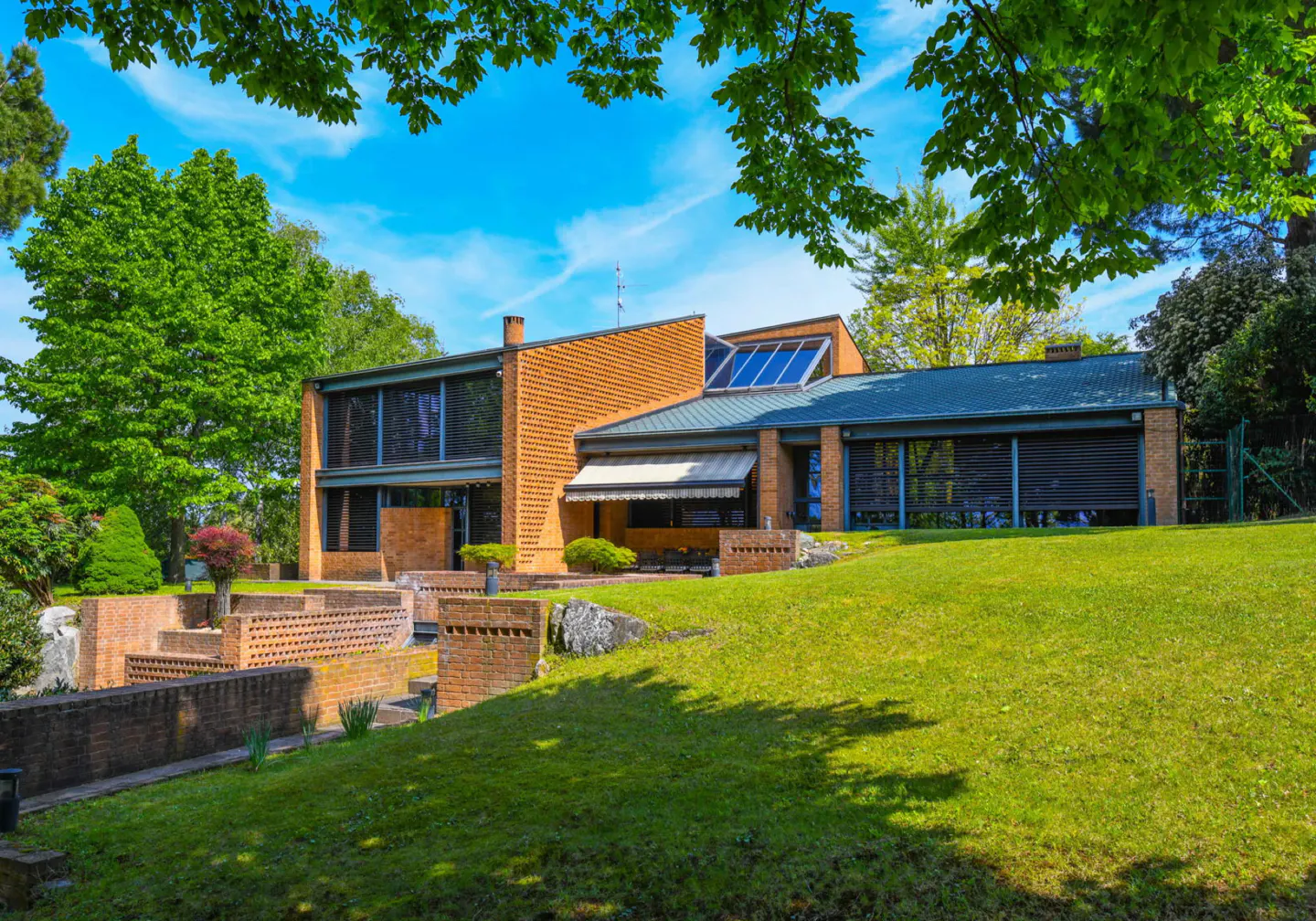 Modern brick house with green lawn and blue sky. The house has a blue roof and solar panels.
