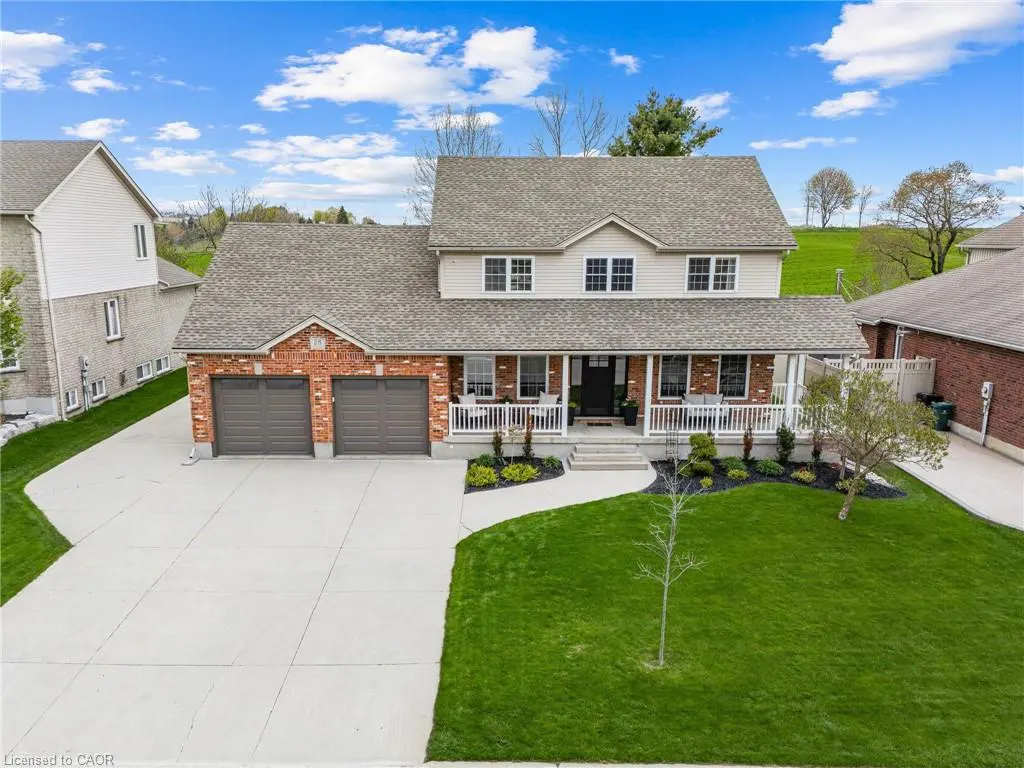 Two-story house with brick and siding, a gray roof, a white porch, and a two-car garage. Green lawn and blue sky.