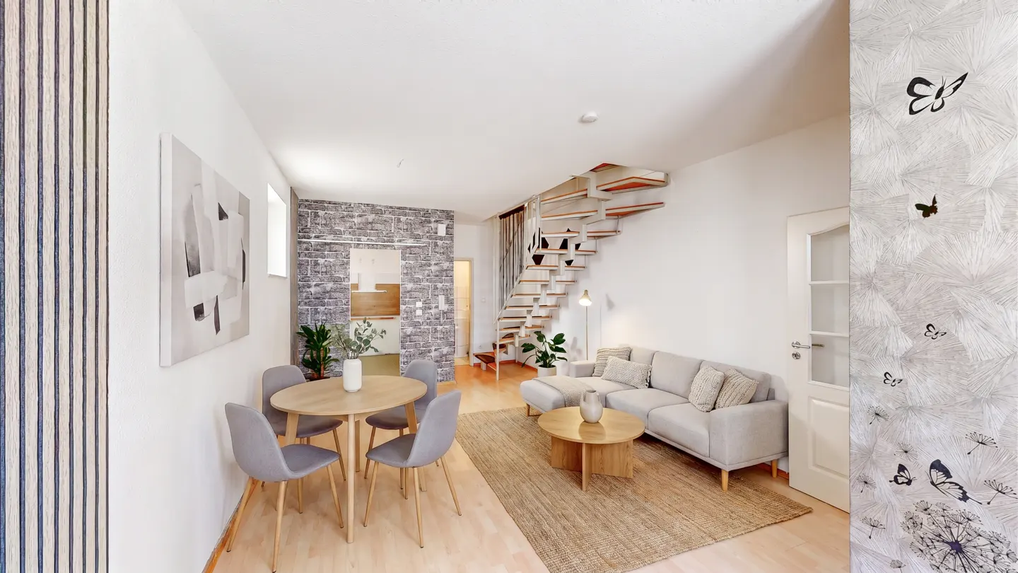 A modern living space with a round table, gray chairs, a gray sofa, and a unique staircase.