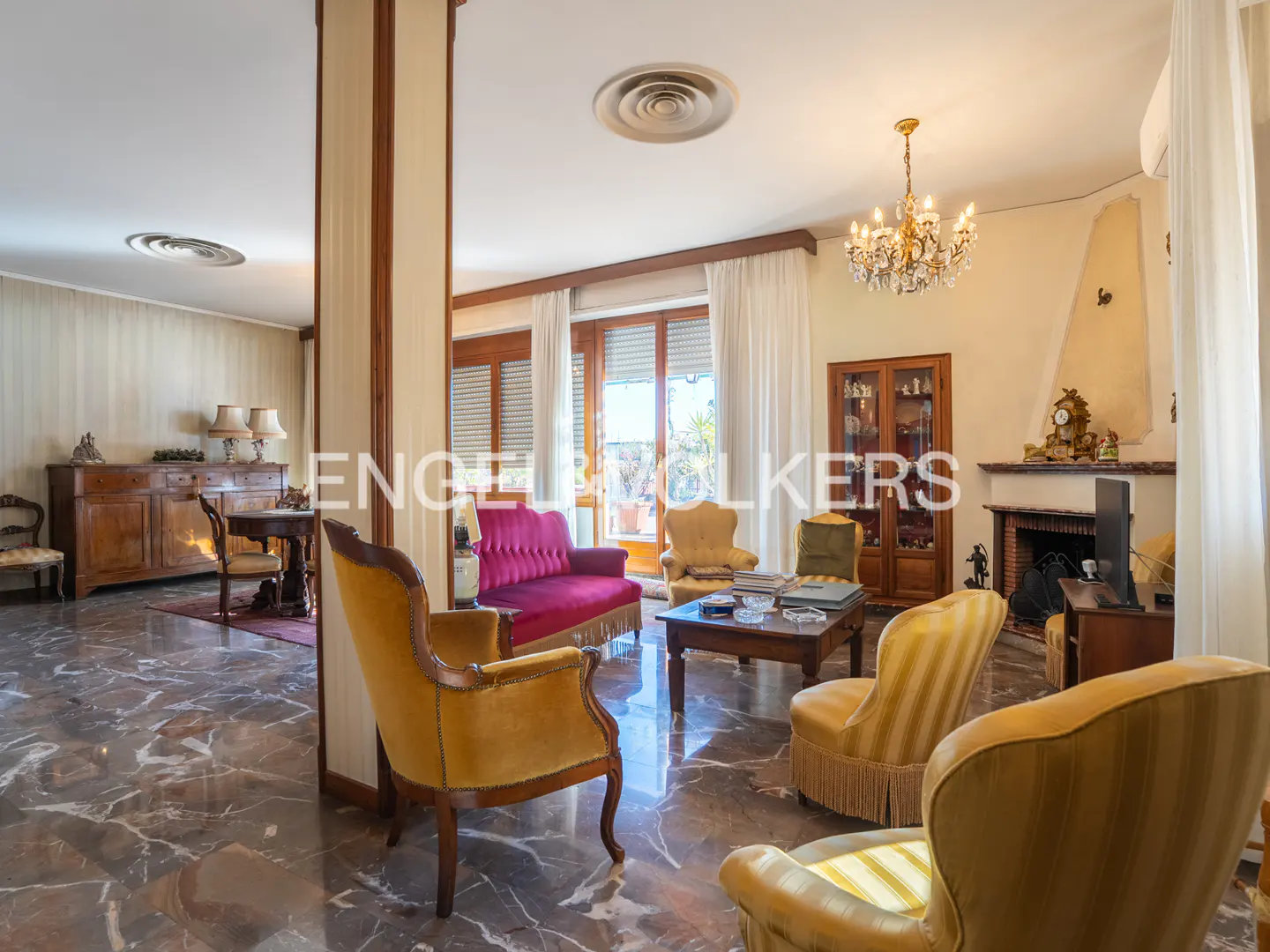 A living room with marble floors, yellow chairs, a red sofa, and a fireplace.