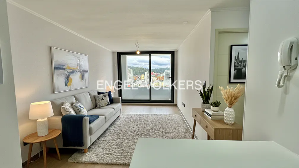 Living room with gray sofa, blue throw, and city view through a sliding glass door. A beige rug covers the floor.