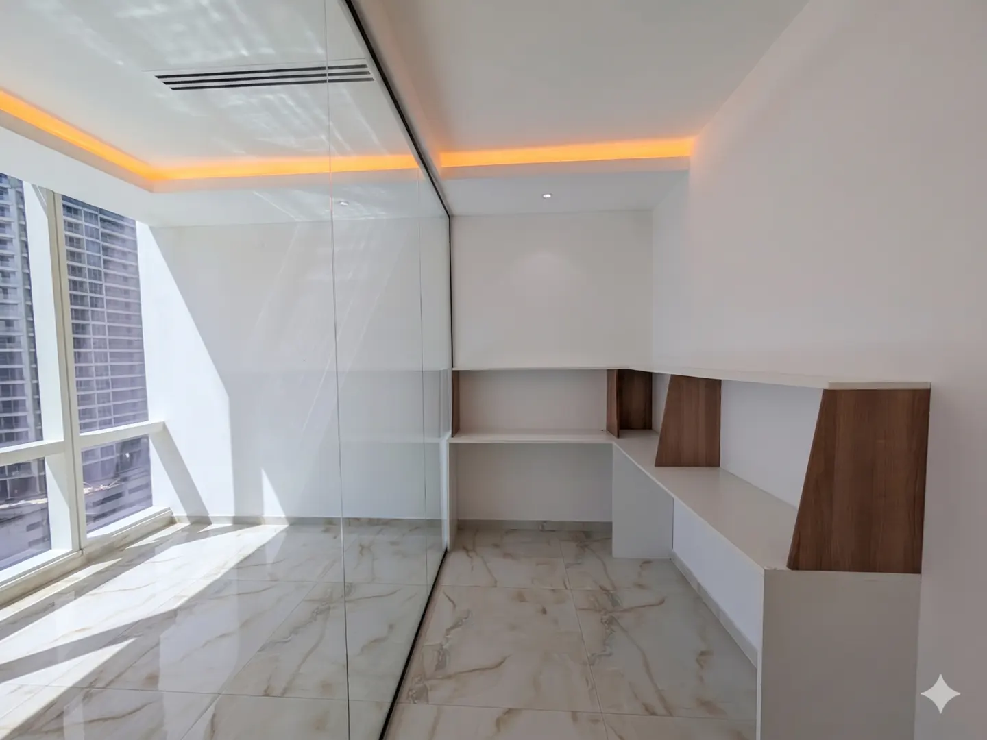 Bright, empty room with white walls, marble floors, and built-in shelves. A large window offers a city view.