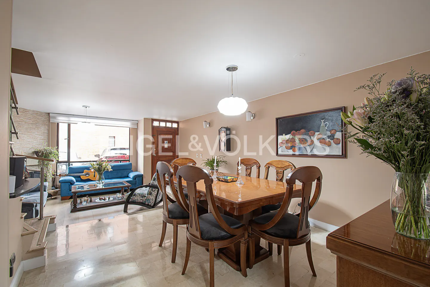 A dining room with a wooden table and chairs, a blue sofa, and a painting on the wall.