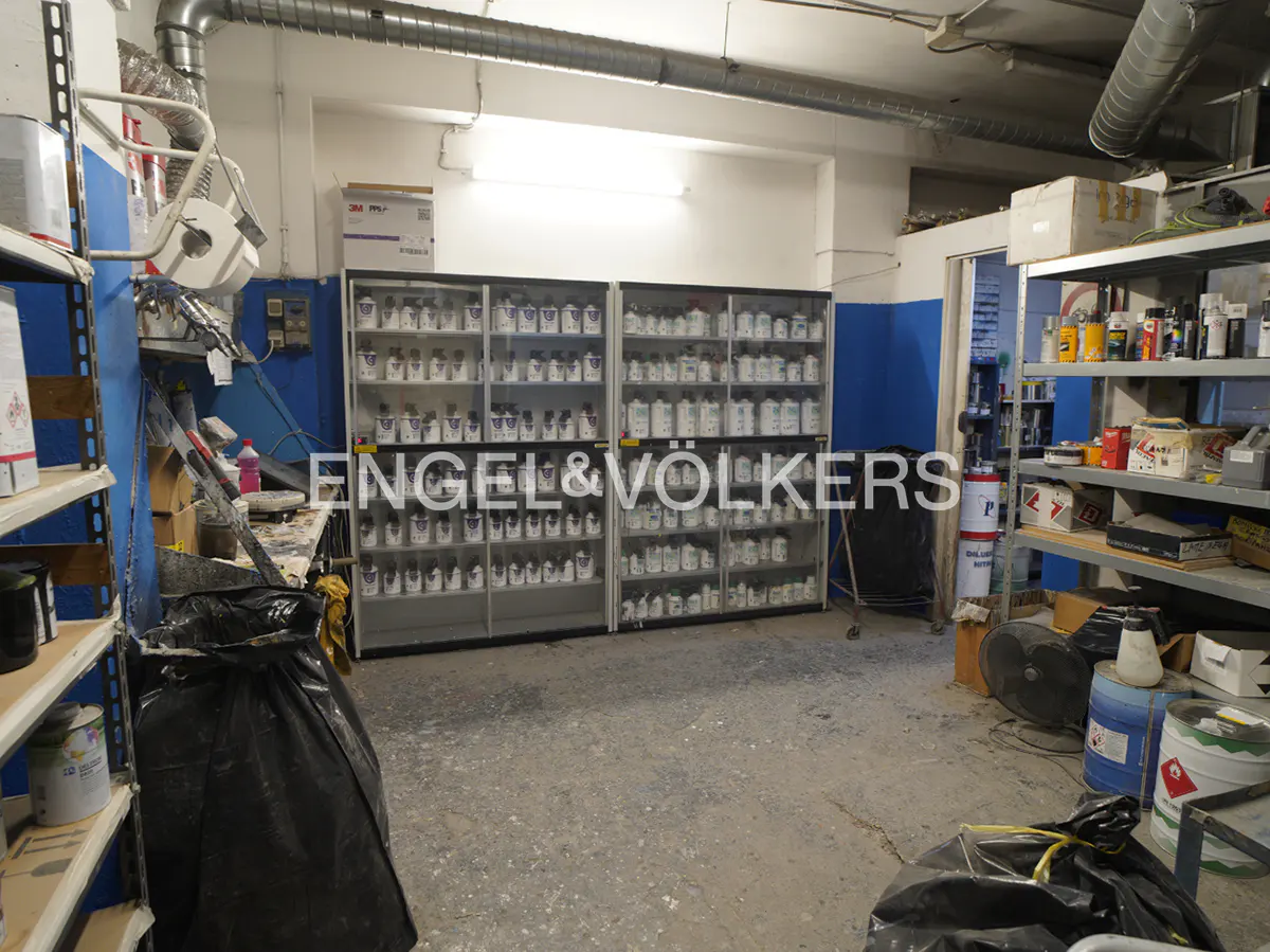 Storage room with shelves filled with paint cans, blue walls, and a concrete floor.