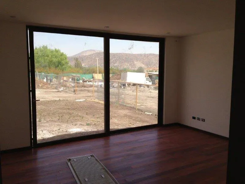 An empty room with dark wood floors and white walls. A large sliding glass door looks out onto a yard with a mountain in the distance.