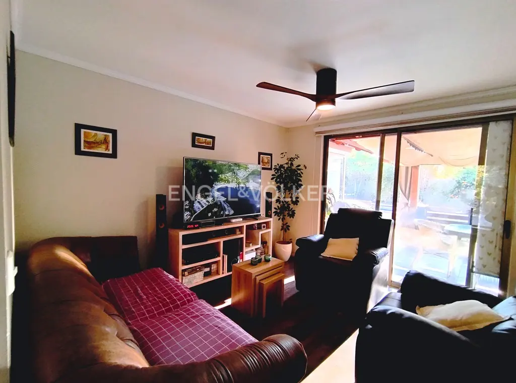 Living room with brown leather sofa, TV, ceiling fan, and sliding glass doors to a patio. Neutral wall color.