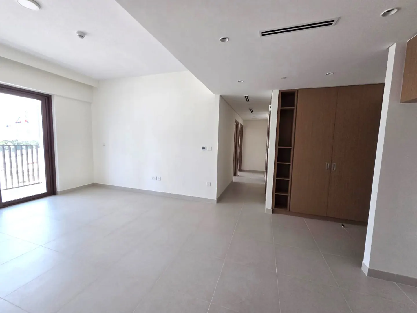 Unfurnished room with gray tile floor, white walls, and a brown closet. A sliding glass door leads to a balcony.