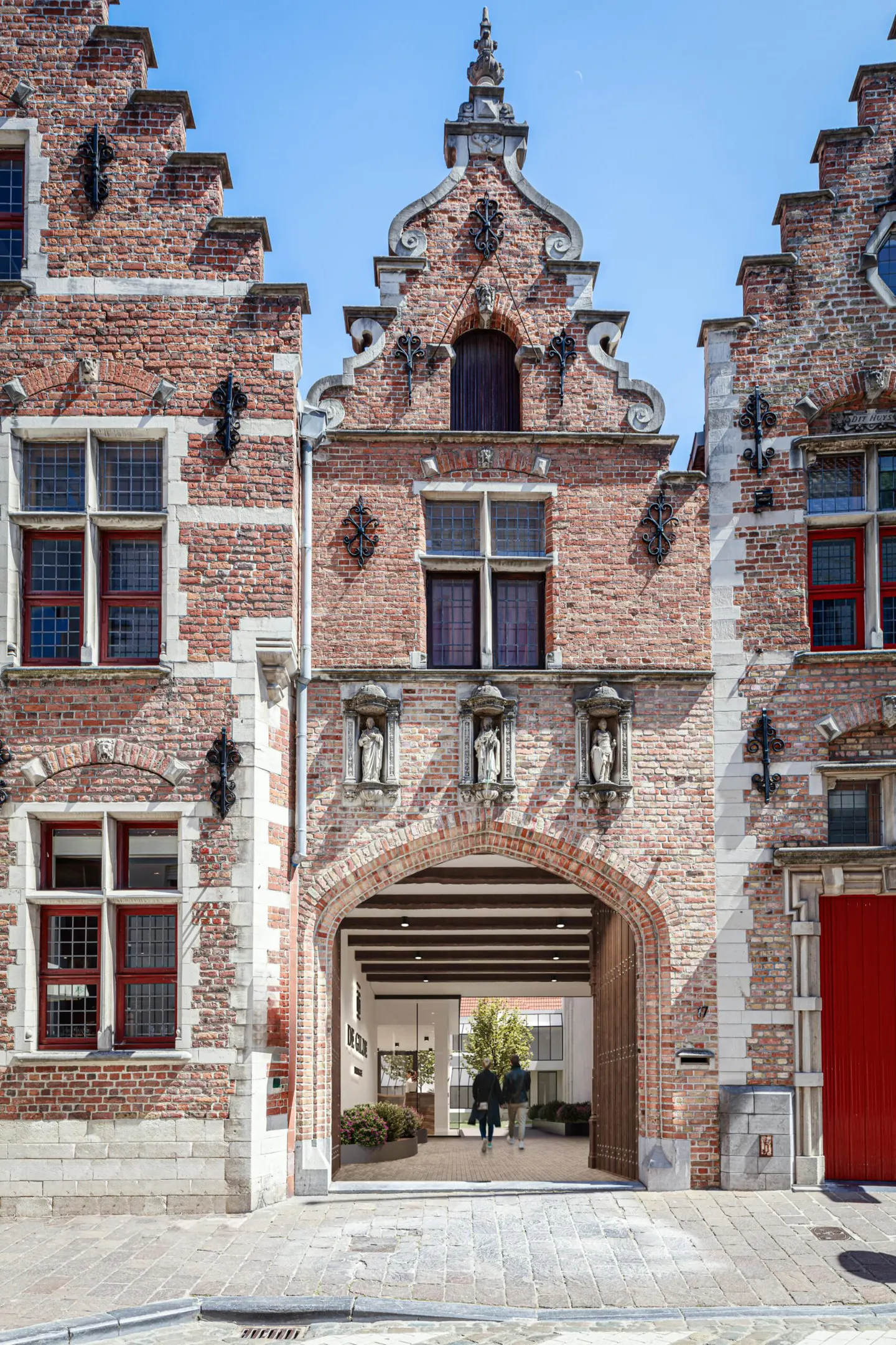 Exterior view of a red brick building with an arched entrance leading to an interior courtyard.