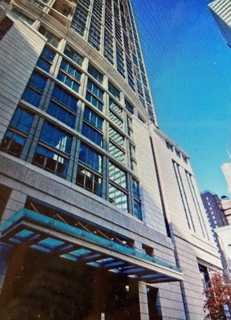 Exterior view of a tall, modern building with many windows and a blue glass awning.