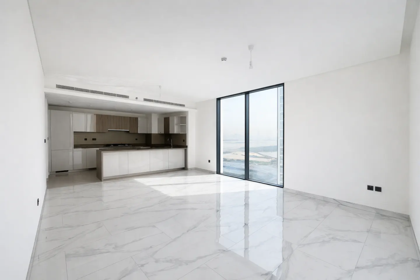 Bright, empty apartment with white walls, marble floors, and a modern kitchen. A large window offers a city view.