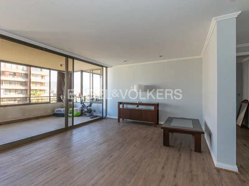 Bright, empty living room with wood floors, gray walls, and a balcony with exercise equipment.