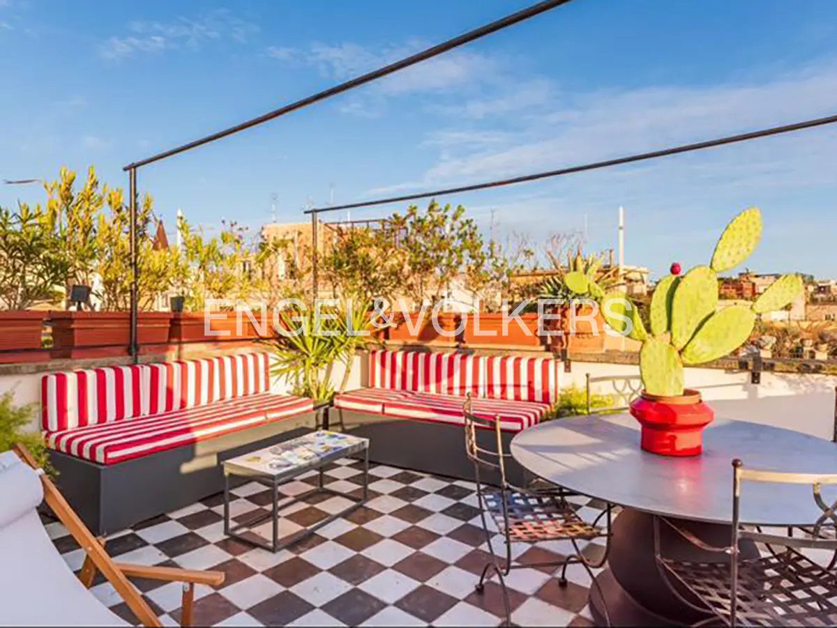 Rooftop patio with black and white checkered floor, red and white striped benches, table, chairs, and cactus in a red pot.
