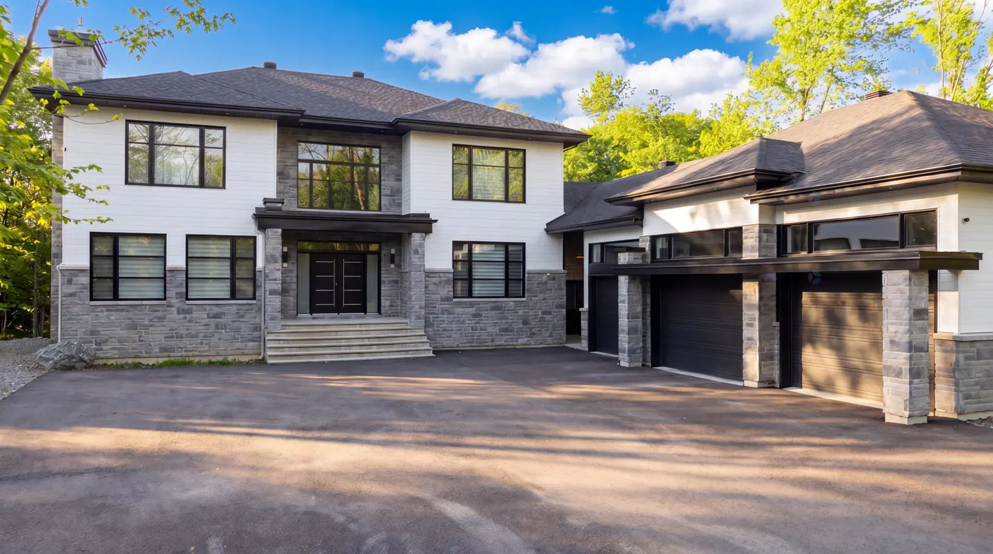 Two-story house with white siding, gray stone accents, black trim, and a two-car garage.