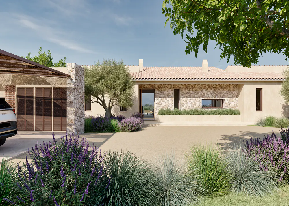 Exterior view of a stone house with a red tile roof, a garage with wooden doors, and lavender bushes in the front yard.
