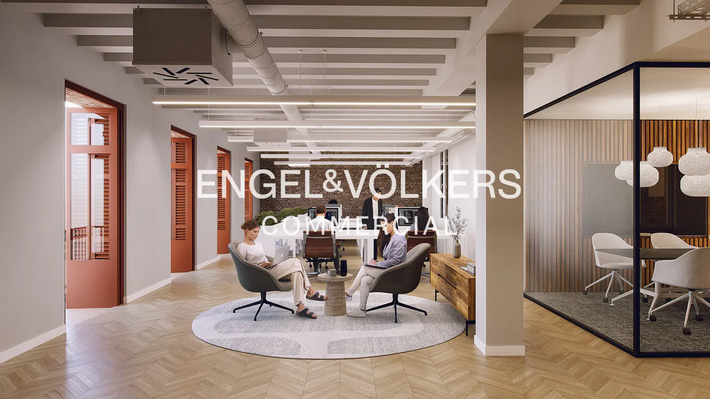 Engel & Völkers commercial office space with two women sitting in chairs using laptops. A conference room is visible in the background.