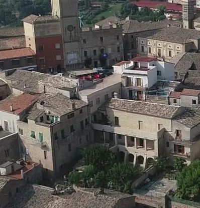 Aerial view of an Italian town with buildings, tile roofs, and a church tower.