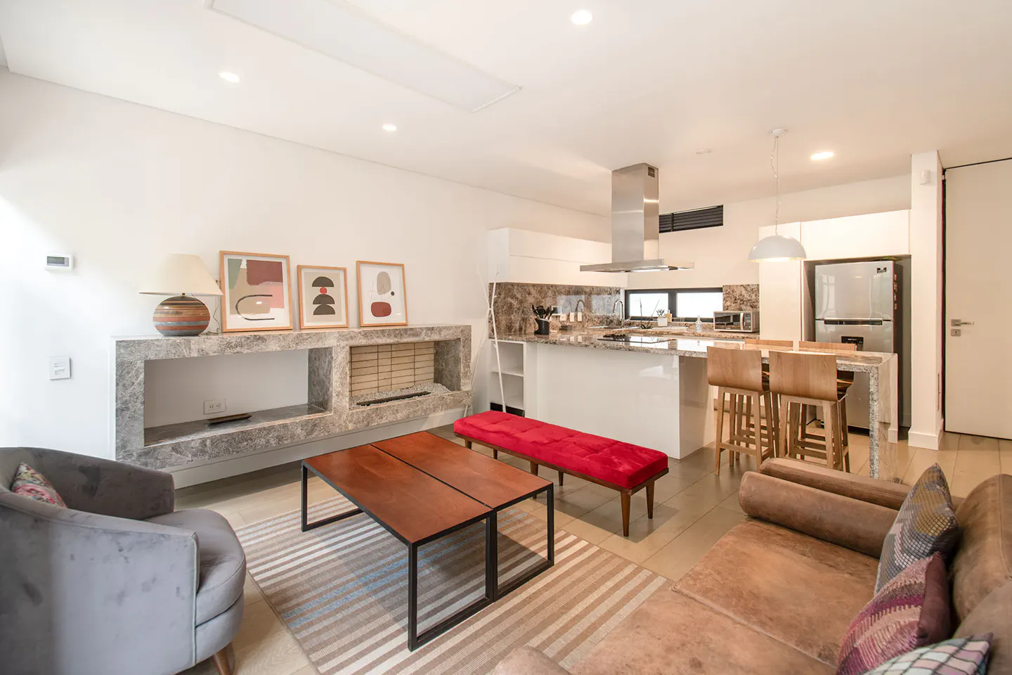 Bright, open-concept living space with a kitchen island, marble fireplace, wood table, and comfortable seating.