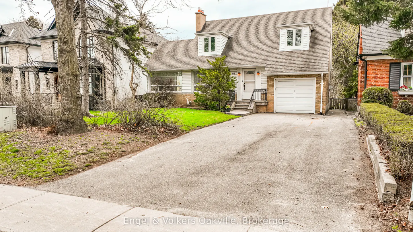 A white, two-story house with a gray roof and a long driveway. Green grass is in the front yard.