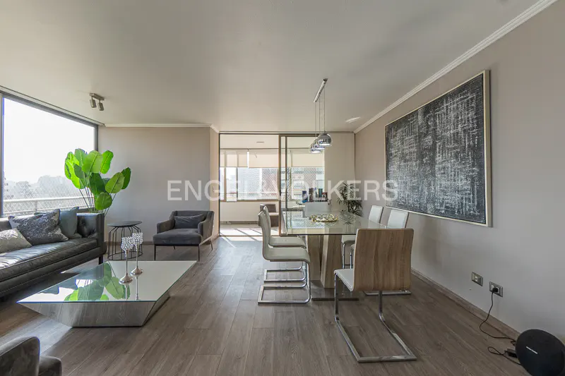 A modern living and dining area with a gray sofa, glass table, and dining set. A large window offers a city view.