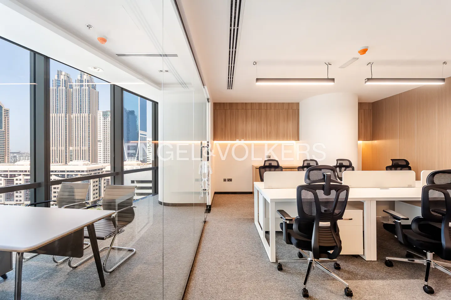 Bright office space with white desks, black chairs, and a large window overlooking a city skyline.
