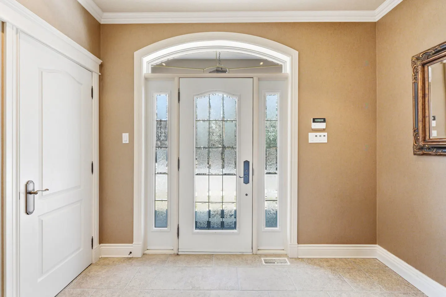 Foyer with white front door with glass panels, white trim, beige walls, and a white door on the left.