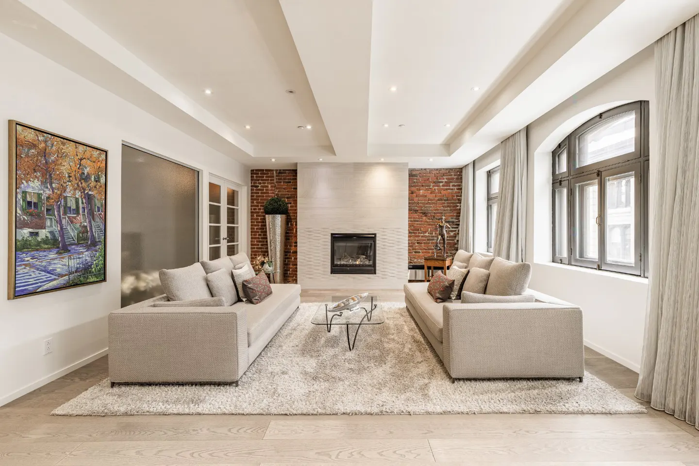 Living room with two beige sofas facing each other, a fireplace, and a painting on the wall.