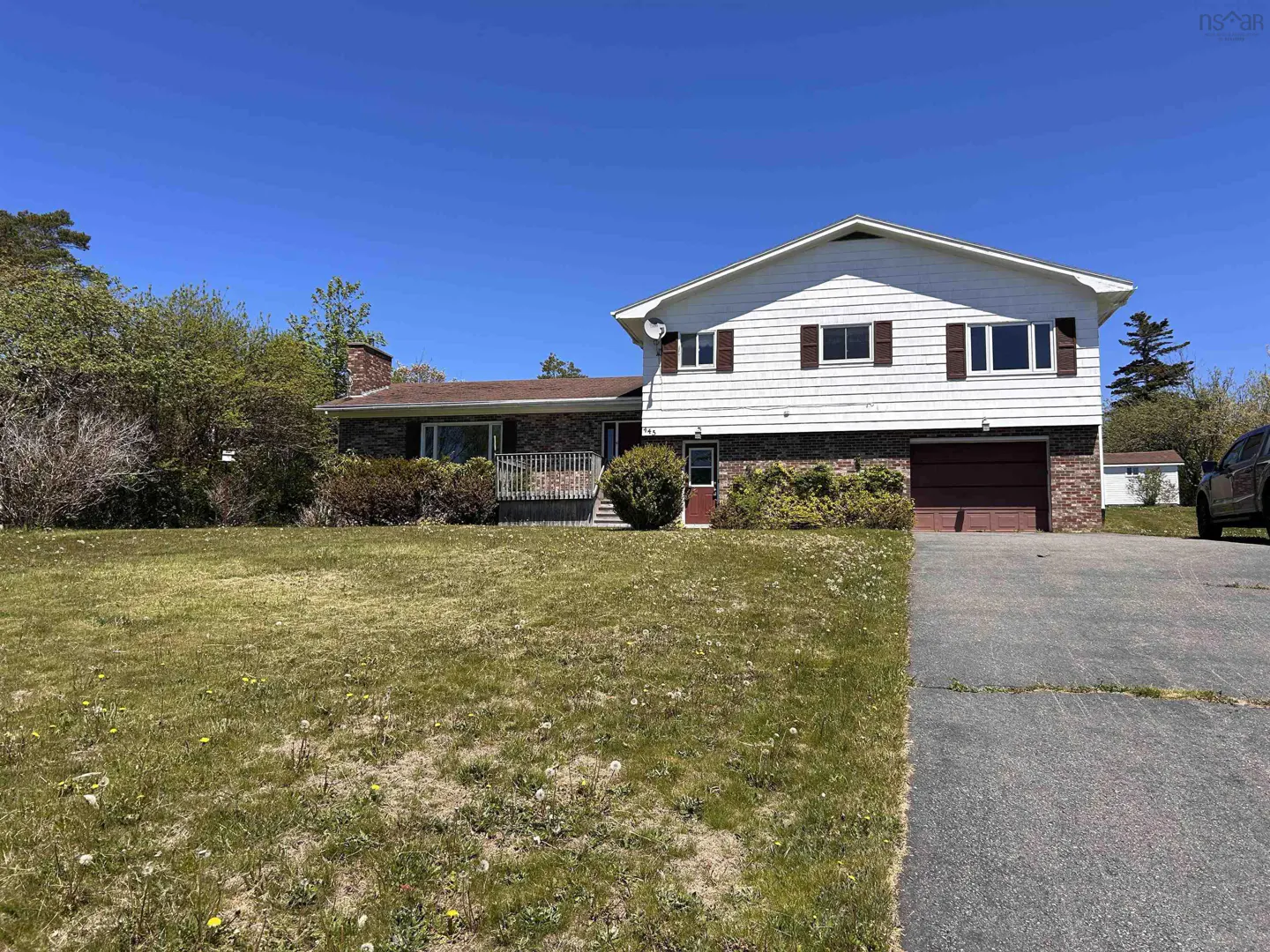 Two-story house with white siding, brick accents, and a brown garage door. A green lawn and driveway lead to the home.