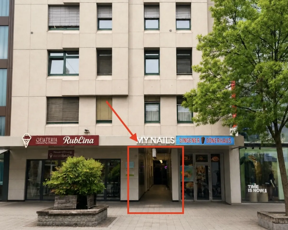 A beige building with shops on the ground floor, including "MyNails" and "Singener Donerhaus", with an arrow pointing to a walkway.