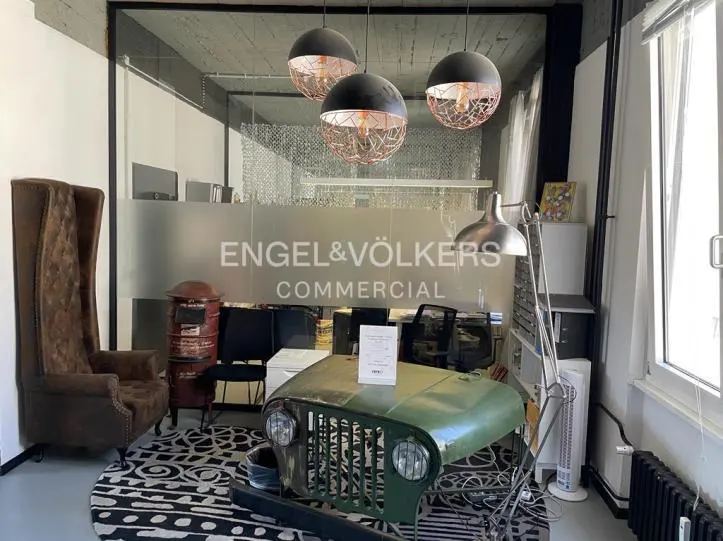Engel & Völkers office interior with a green Jeep grill table, brown armchair, and modern lighting fixtures.