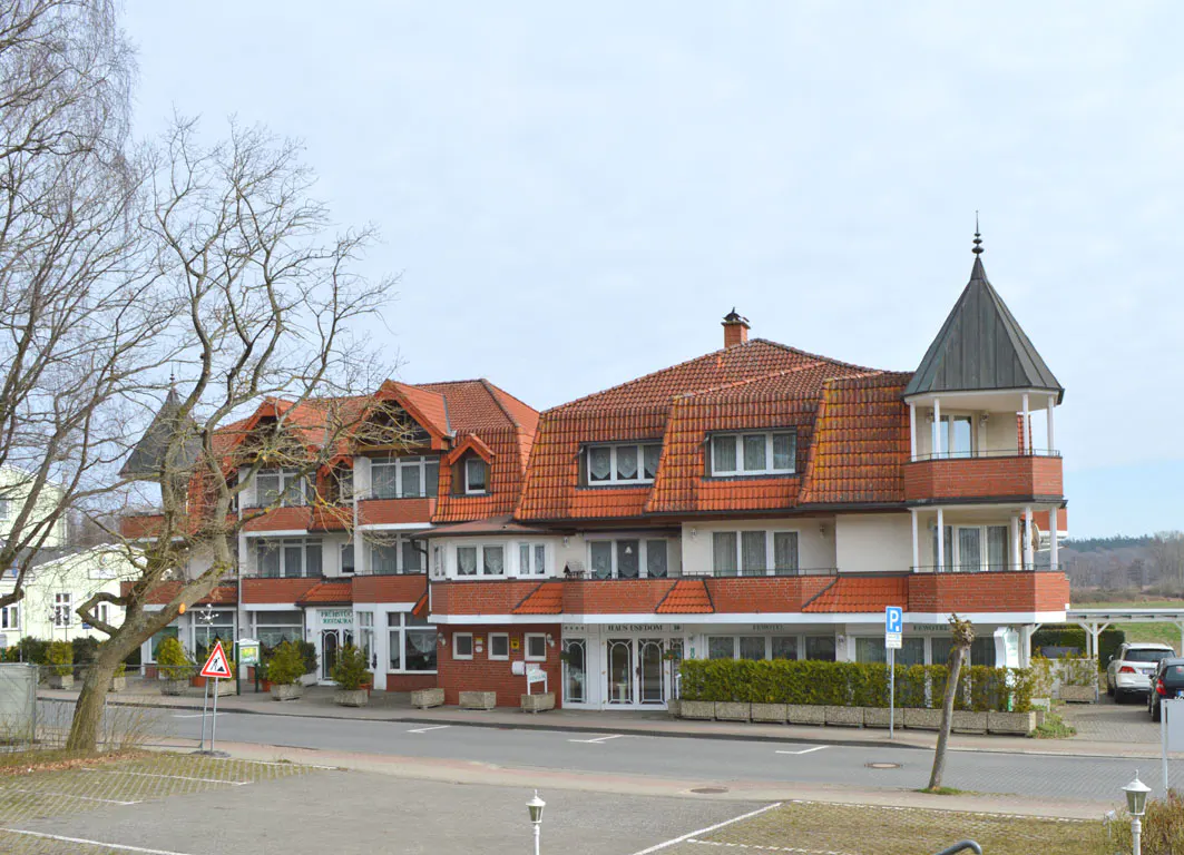 Three-story building with red tile roof and white walls, with a turret on the right side.