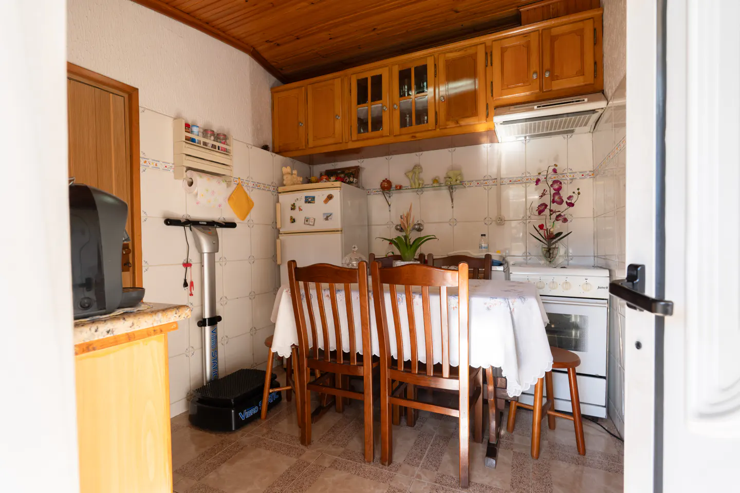 A kitchen with wood cabinets, a white fridge, and a dining table with chairs.