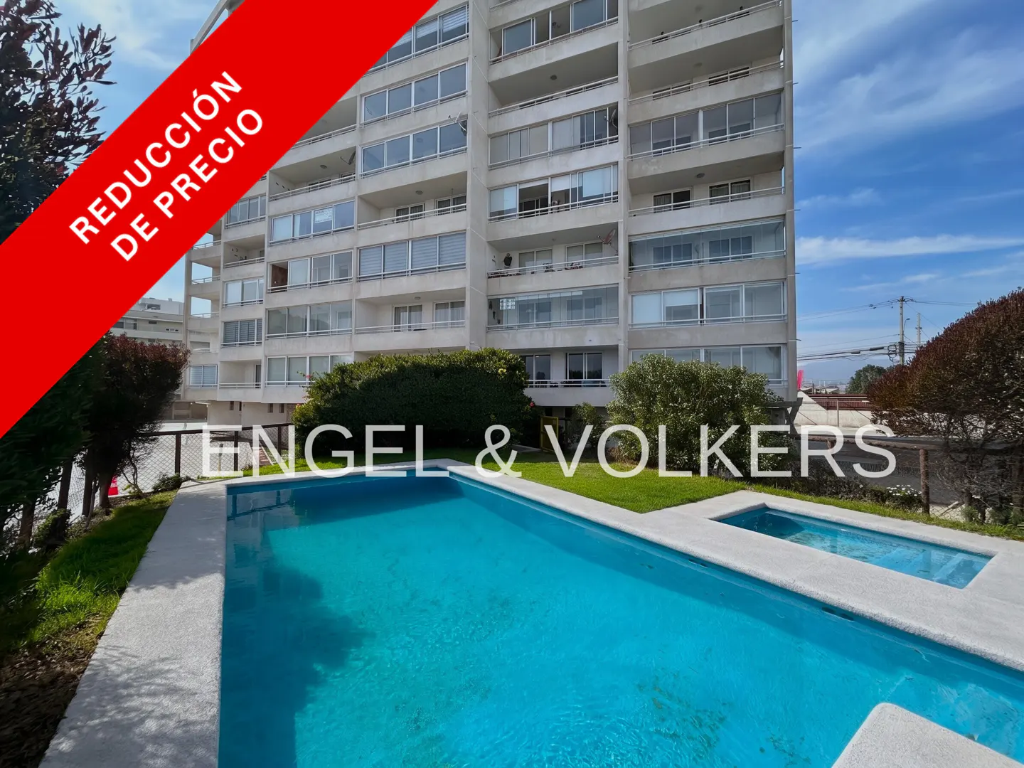 A bright blue swimming pool in front of a tall white apartment building with a red "Price Reduction" banner overlay.