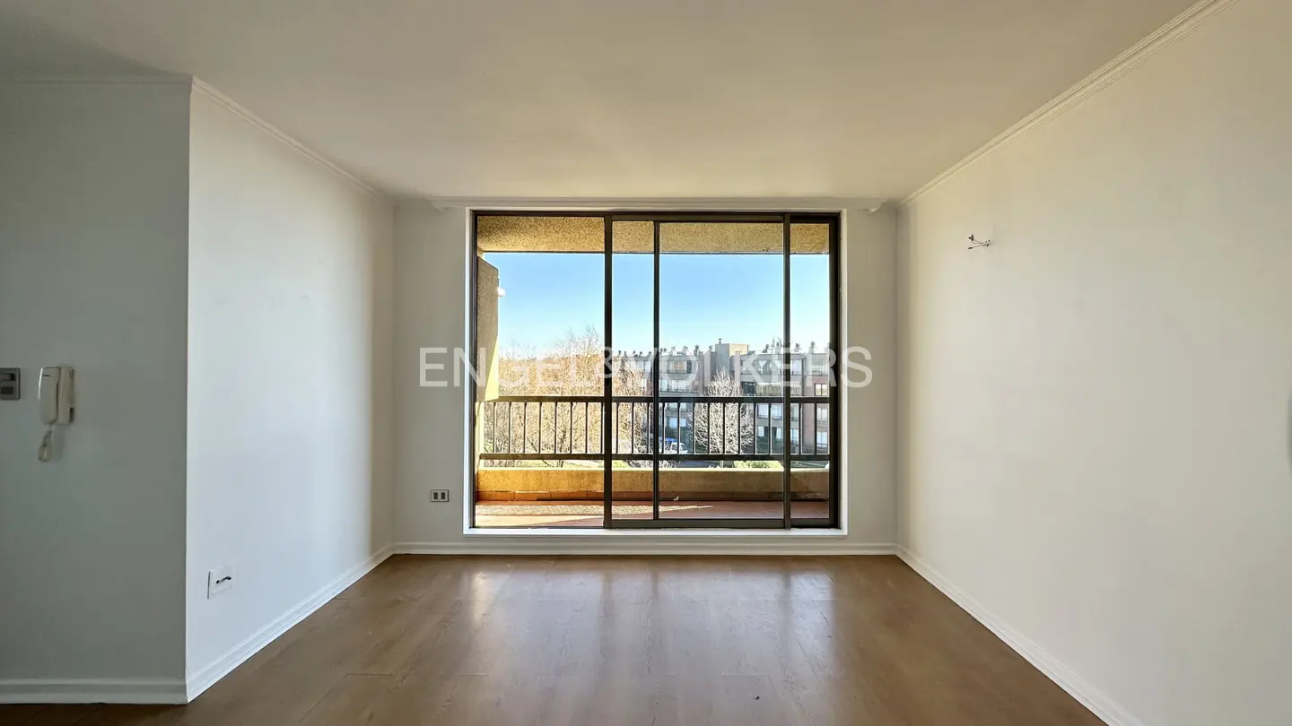Empty room with wood floors and white walls. Large sliding glass doors lead to a balcony with a city view.