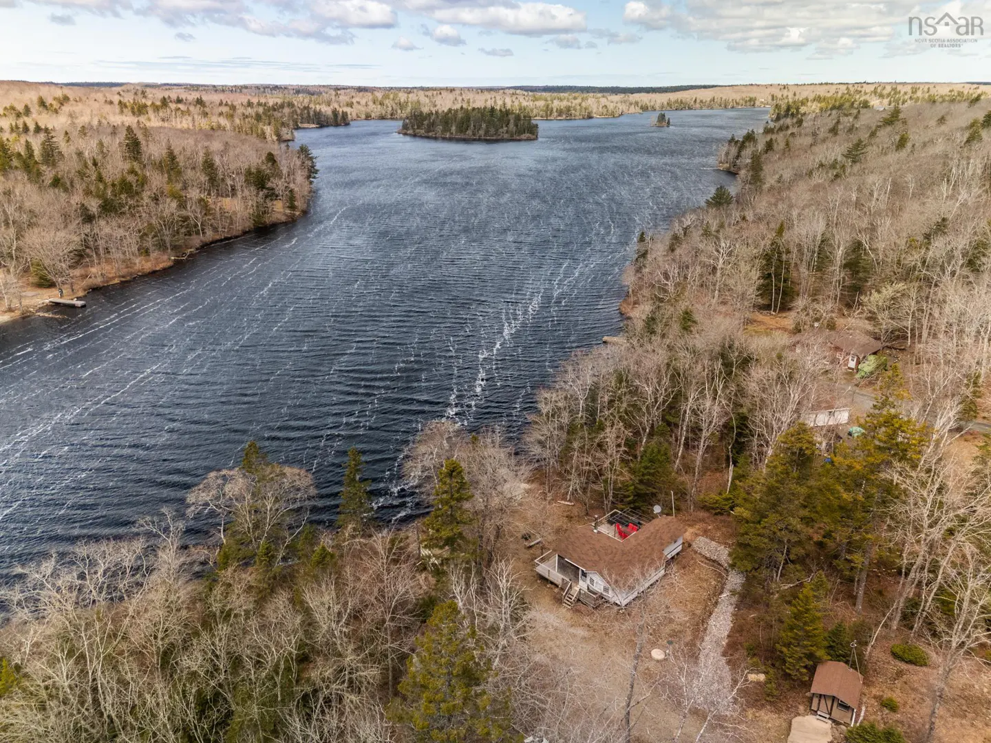 Aerial view of a lake surrounded by trees, with a house visible on the shoreline.