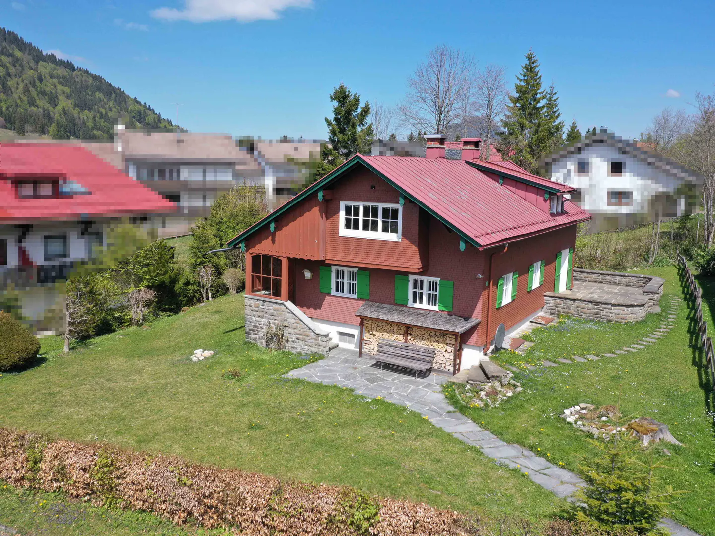 Exterior view of a red house with green trim and shutters, a red roof, and a green lawn.