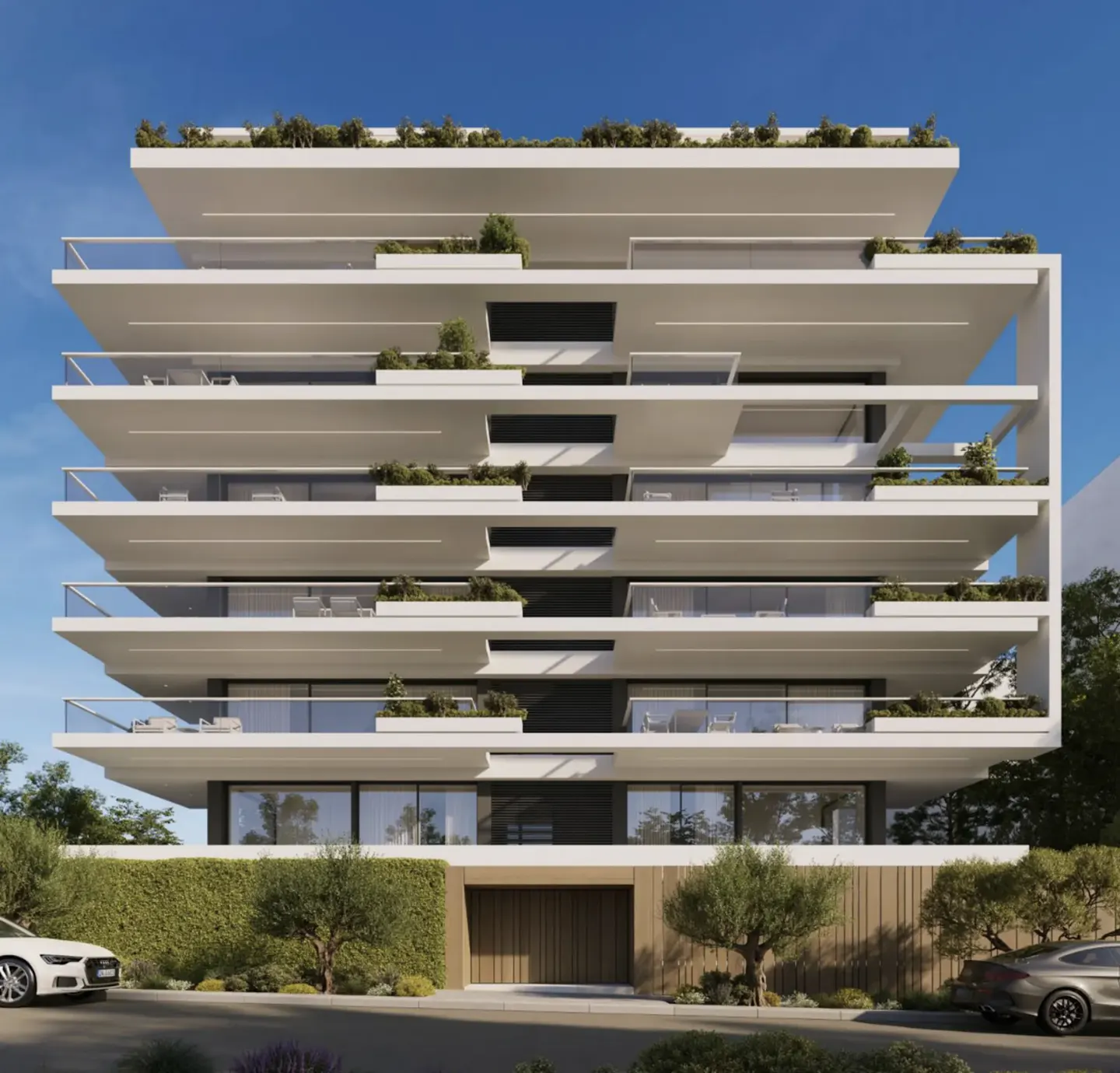 Modern white apartment building with layered balconies and greenery, set against a blue sky. Cars parked in front.