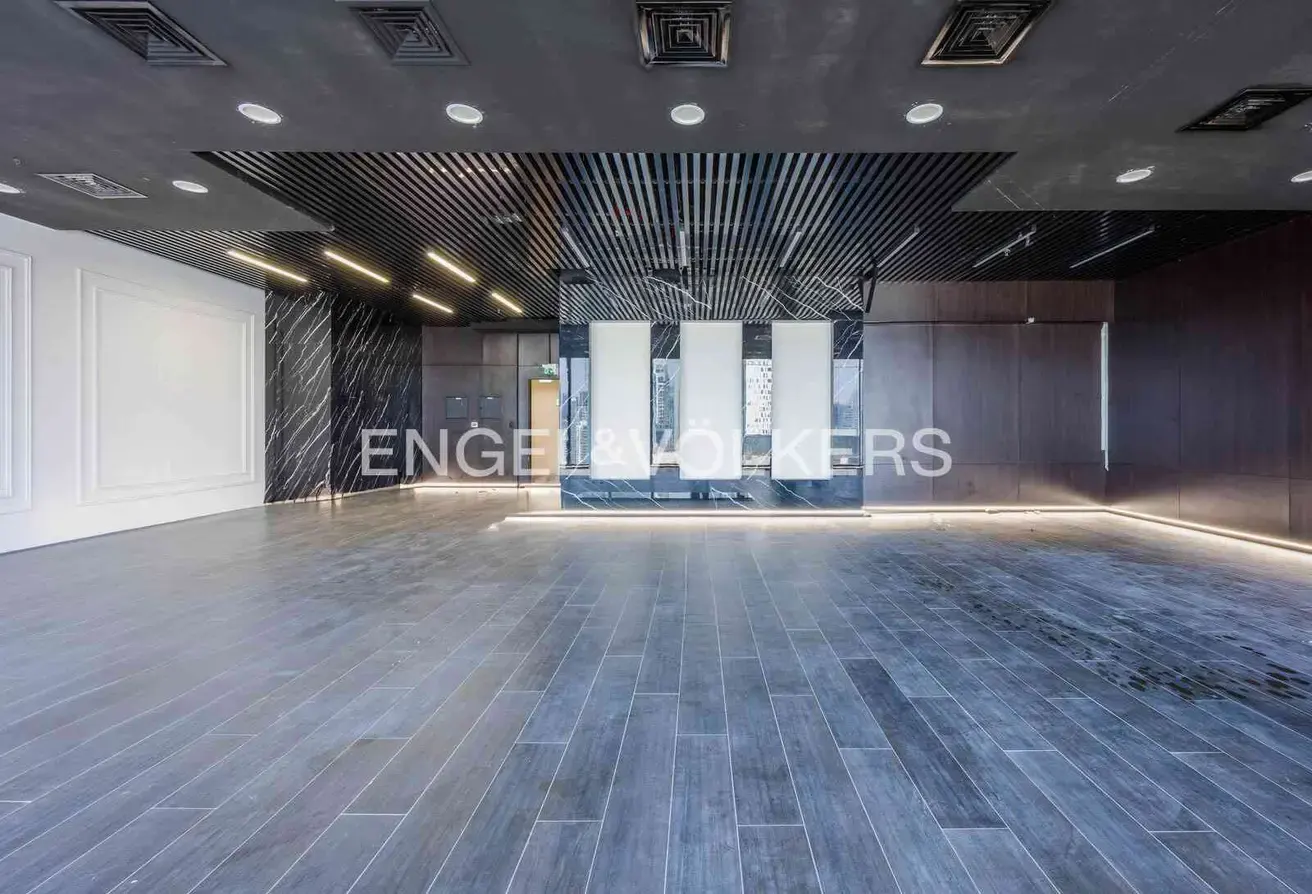 Empty commercial space with gray wood-look tile floor, black marble accent walls, and a black slatted ceiling with recessed lighting.