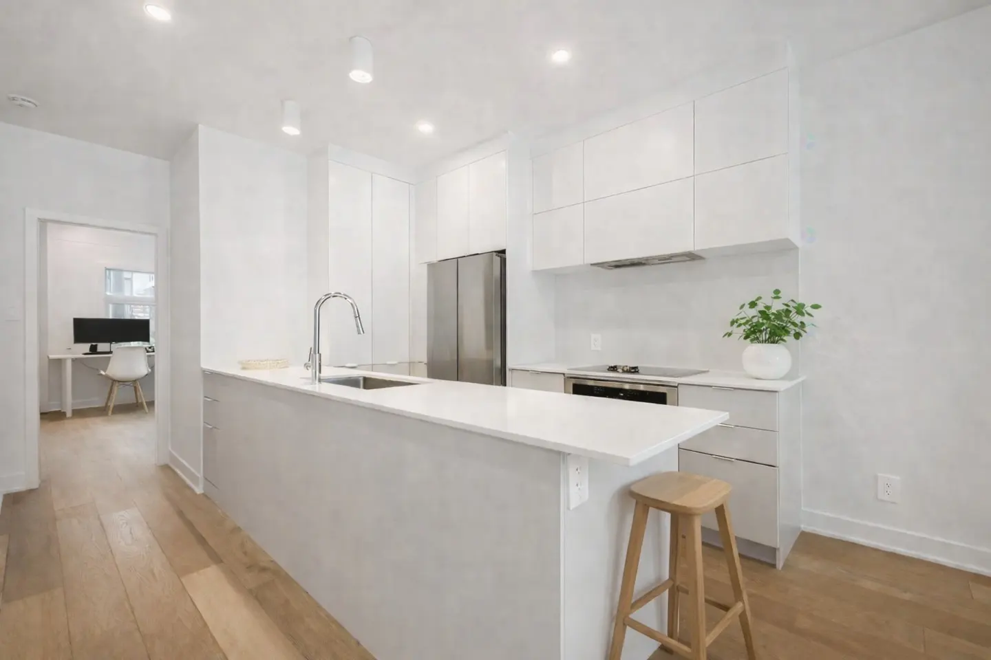 Bright, modern kitchen with white cabinets, stainless steel appliances, and a light wood floor. A kitchen island has a sink and a wooden stool.