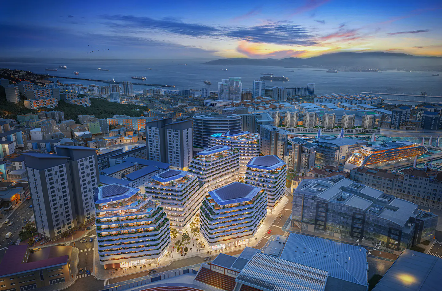Aerial view of modern, tiered apartment buildings in a city by the sea at dusk.