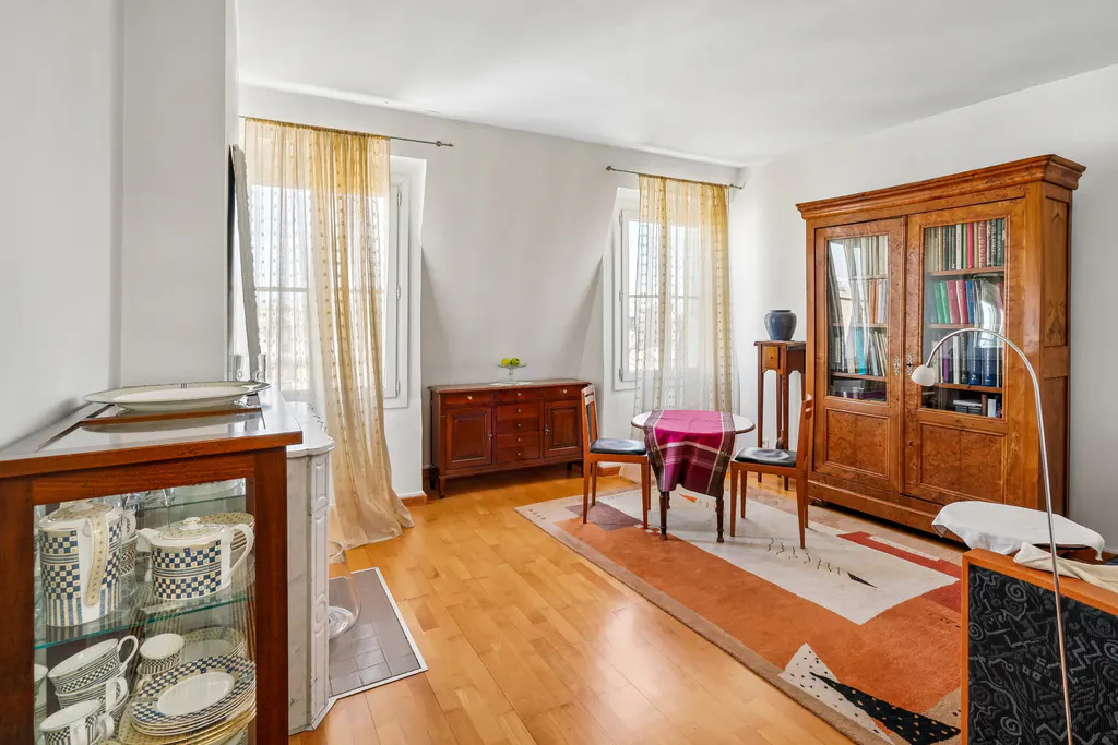 Bright dining room with hardwood floors, a wooden hutch, a small table with two chairs, and a patterned area rug.