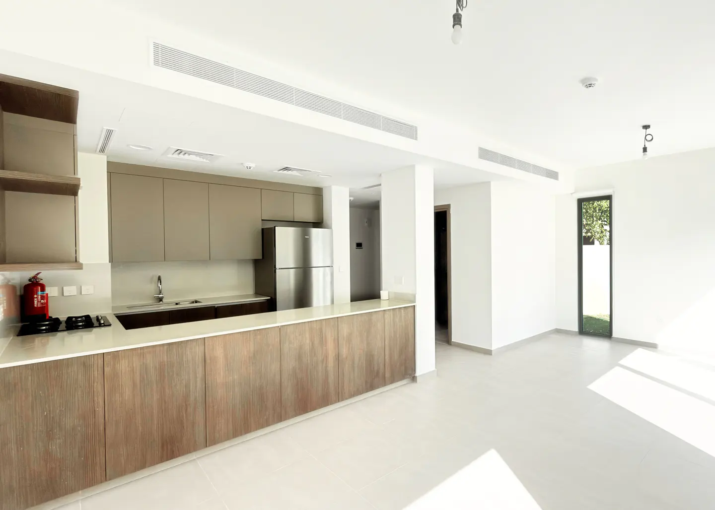 Bright, modern kitchen with wood cabinets, stainless steel appliances, and white countertops. Open floor plan with a view to the outside.