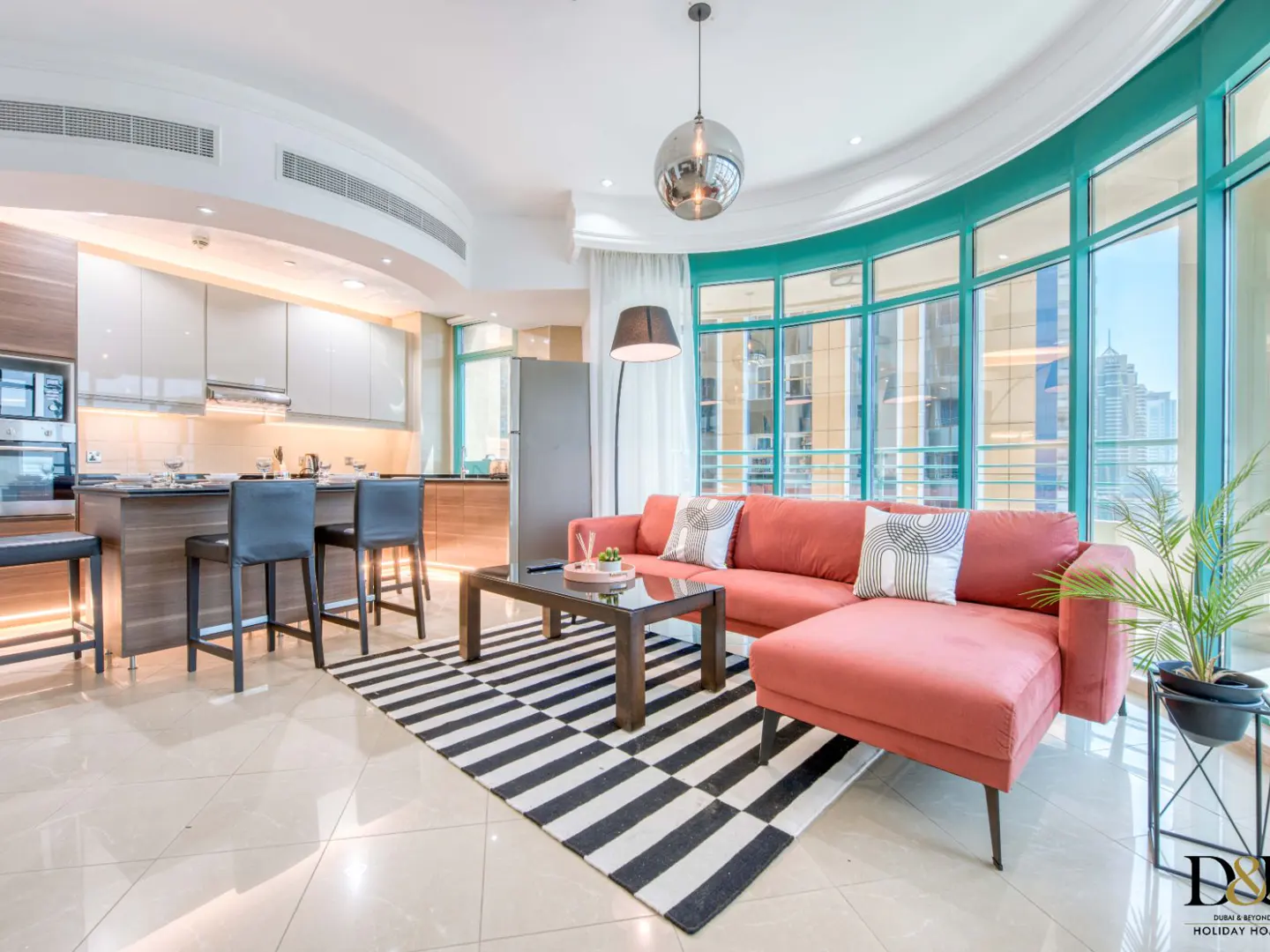 Bright, modern apartment interior with coral sofa, black and white rug, and turquoise window frames overlooking a city view.