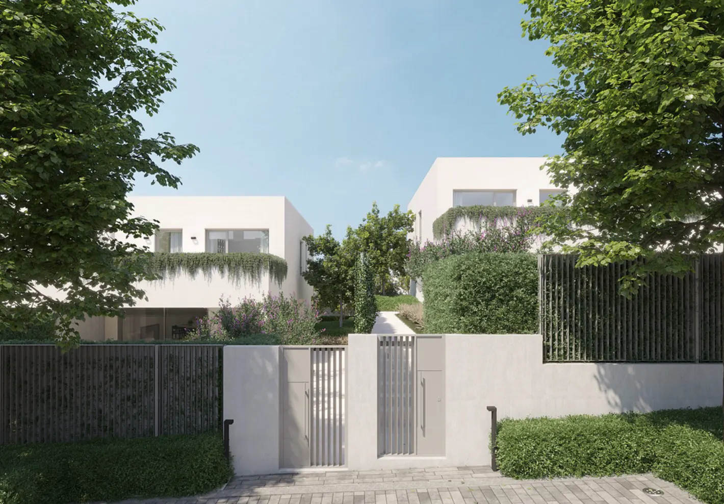 Two modern white houses with green foliage, viewed through a gray metal gate and fence. Blue sky.