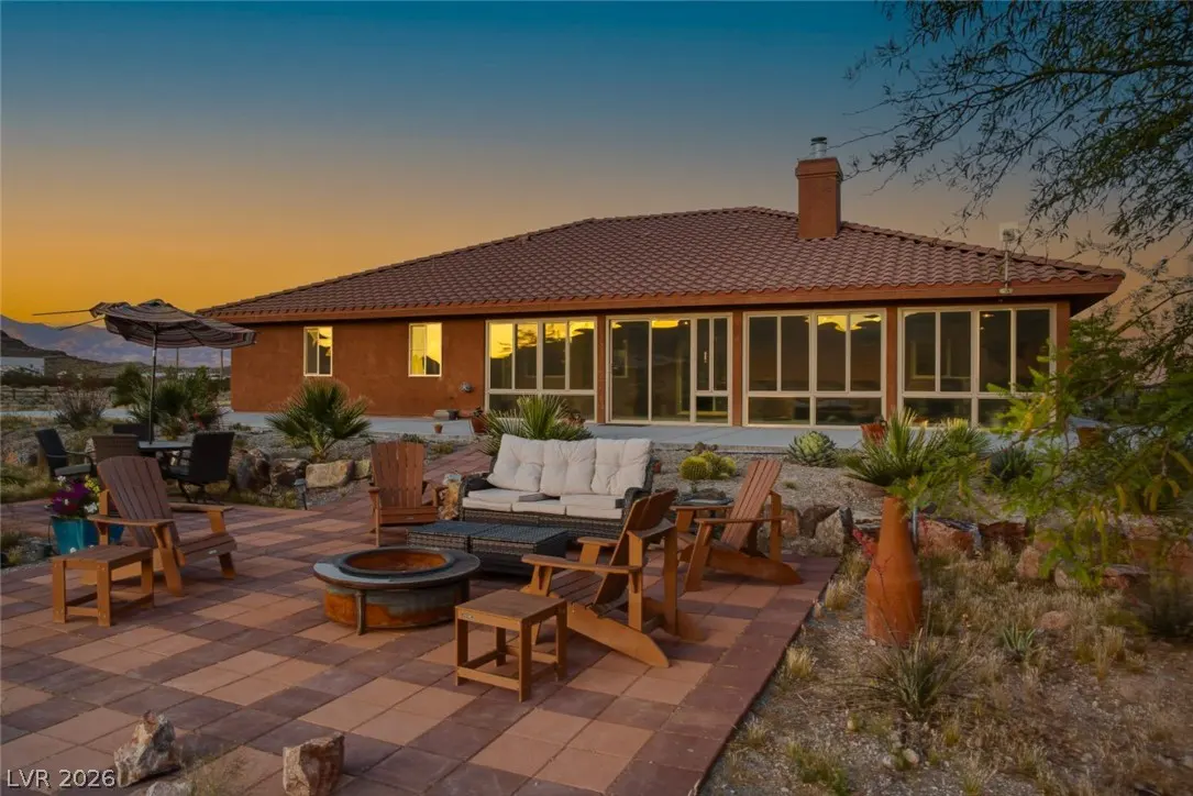 Exterior view of a single-story home with a red tile roof and an outdoor patio with a fire pit and seating.