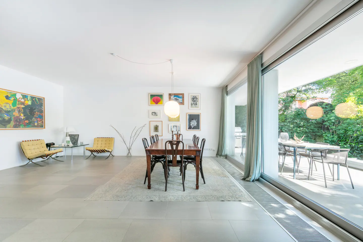 Bright, modern dining room with a dark wood table and chairs, art on the wall, and a patio view.