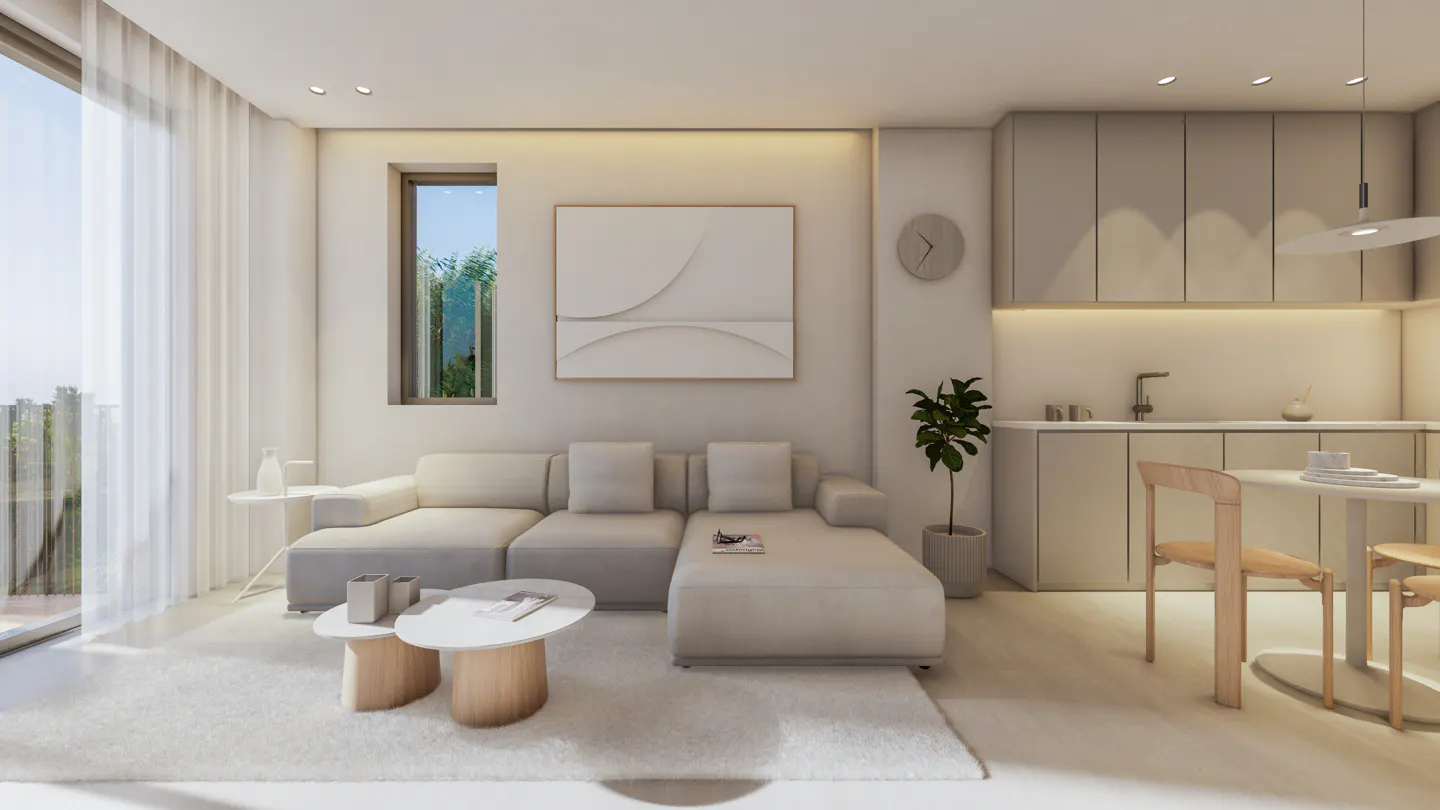 Bright, modern living room with a beige sectional sofa, round coffee tables, and a white rug. A kitchen area is visible in the background.