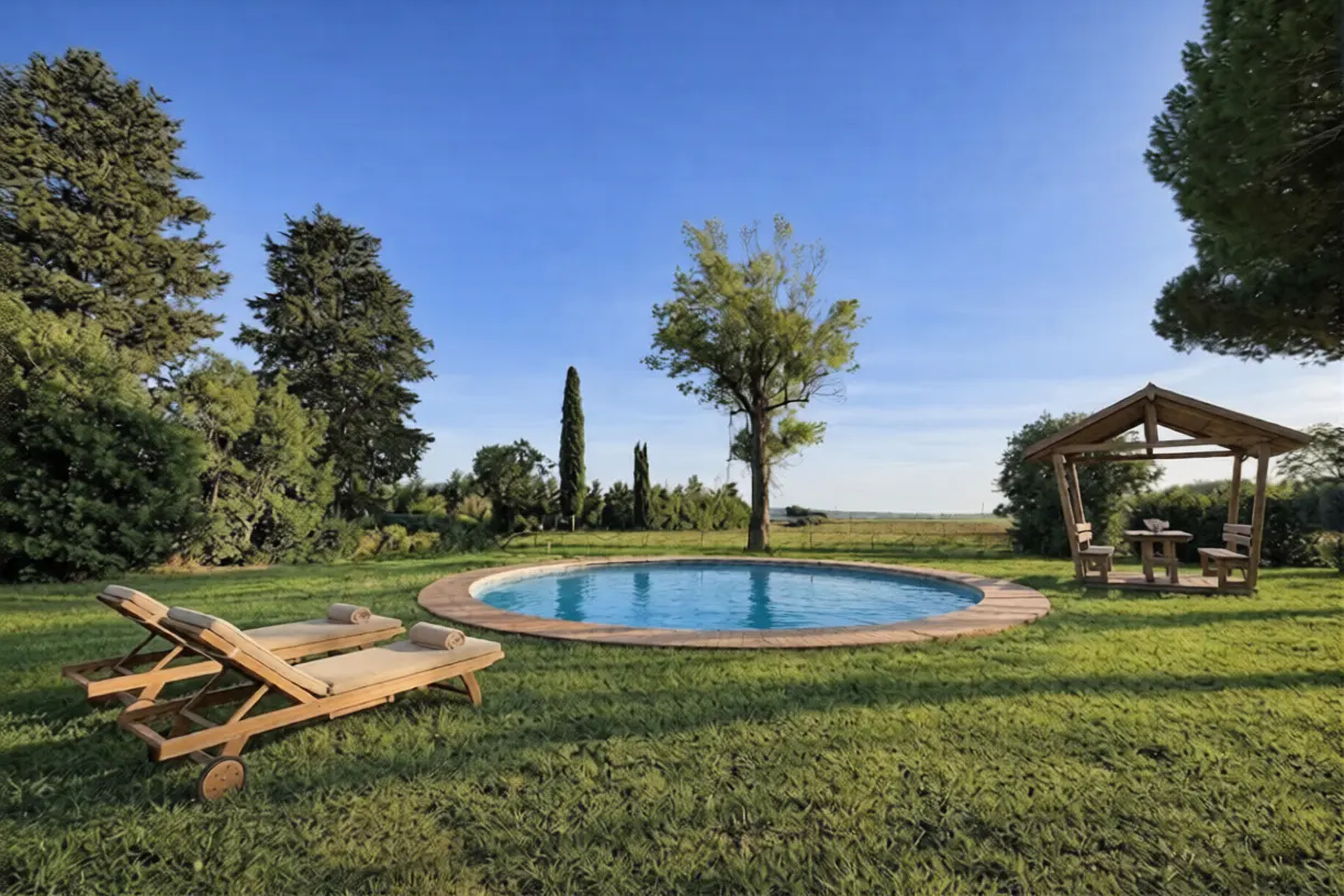 A sunny backyard with a round pool, lounge chairs, and a gazebo on green grass.