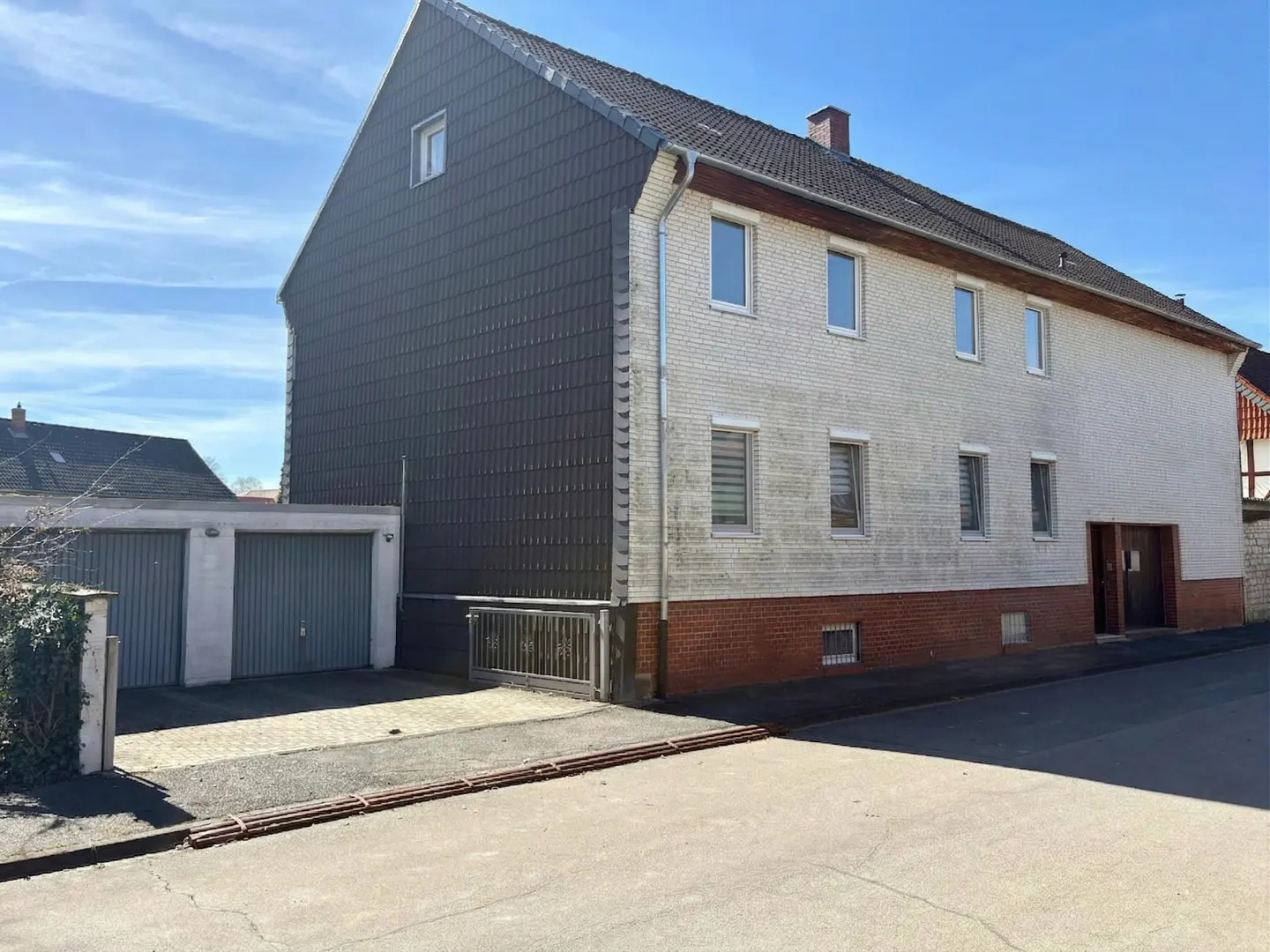 Two-story house with a gray tiled facade and a white brick facade, plus a two-car garage.
